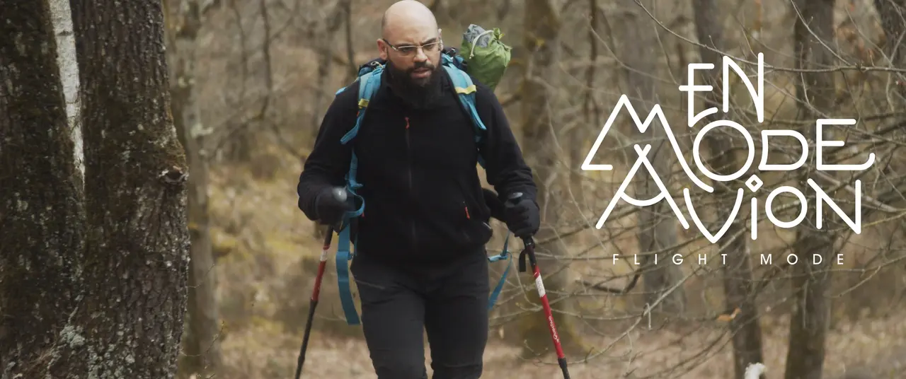 Samir marche en forêt, bâtons à la main. À droite, le titre En Mode Avion.