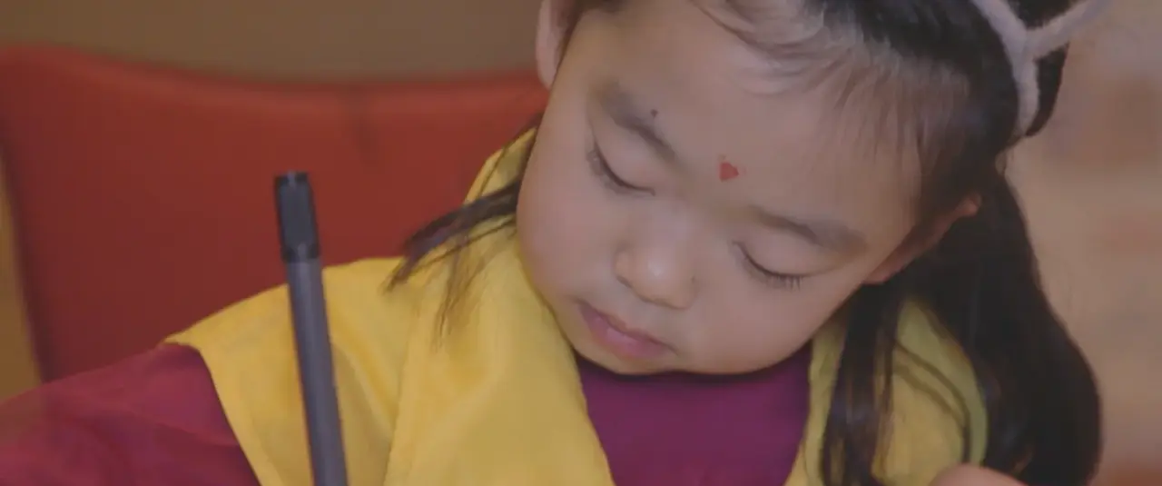 Une petite fille concentrée, un feutre à la main, pendant une épreuve.
