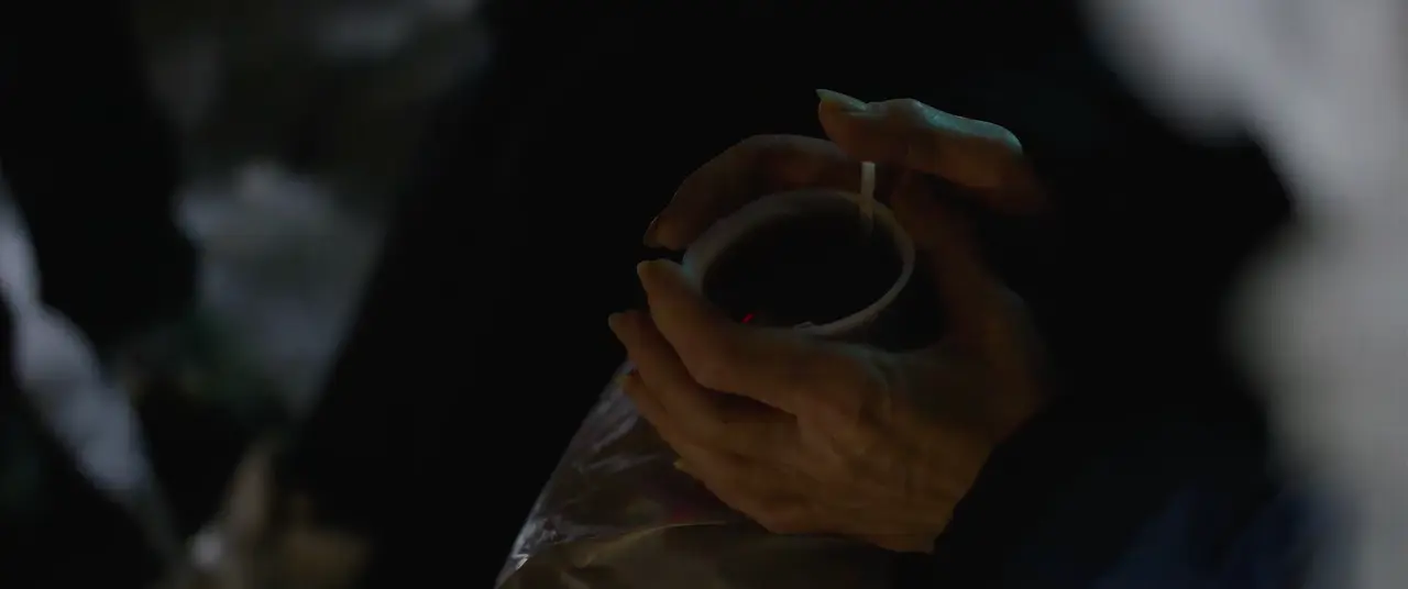 Dans la nuit, des mains tiennent un gobelet fumant.