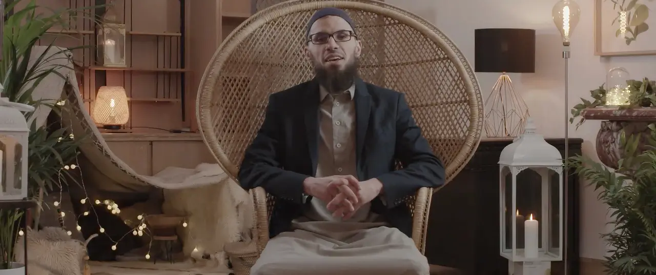 Un homme assis dans un grand fauteuil en rotin, entouré de lanternes et de plantes.