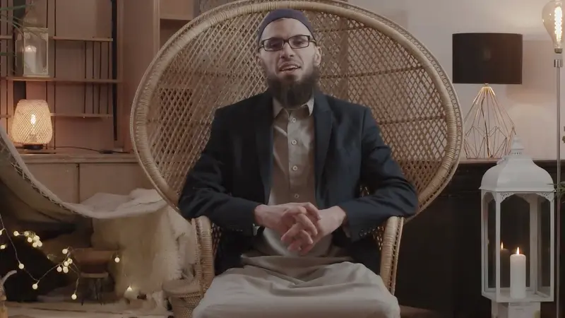 Un homme assis dans un grand fauteuil en rotin, entouré de lanternes et de plantes.